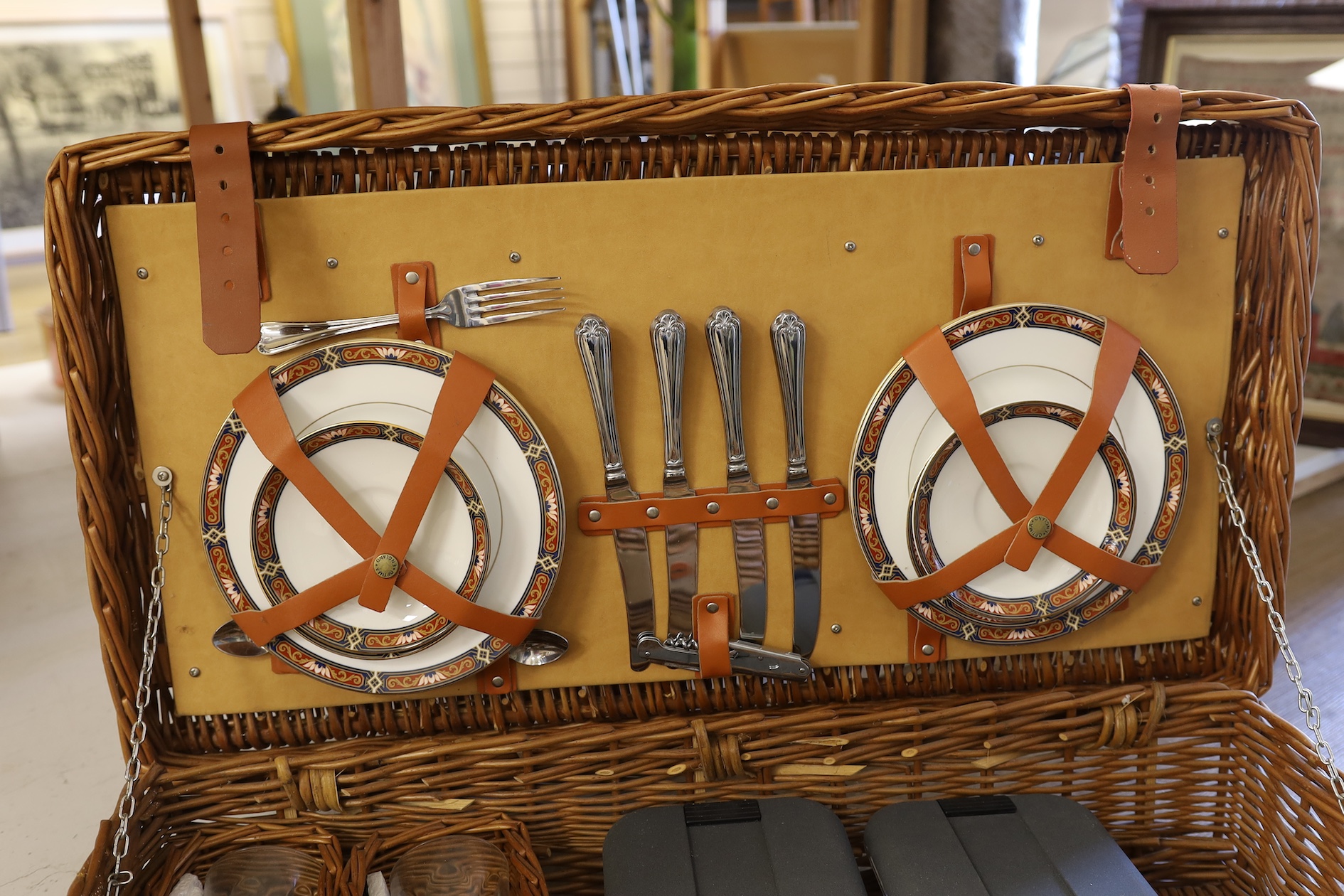 A Harrods wicker picnic hamper for four persons, with Wedgwood plates, cups and saucers, plated cutlery and wine glasses. Condition - good